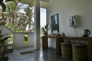 a room with a desk and a window with a palm tree at The Stables Oceanfront Hotel Midigama in Midigama East