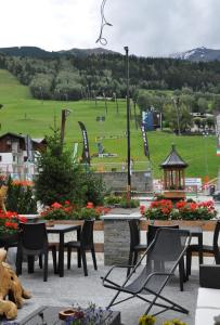 um pátio com mesas e cadeiras e um campo de futebol em Hotel Ambassador Bormio em Bormio