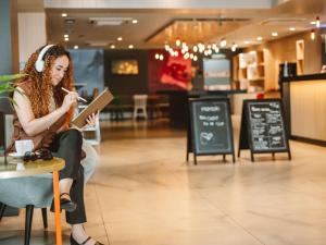 uma mulher sentada numa cadeira a ler um livro em ibis Juazeiro do Norte em Juazeiro do Norte