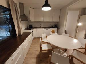 a kitchen with a white table and white chairs at Arctic Aurora Villa with a Lappish Grill Hut - Northern Lights and Private Sledding Hill in the Backyard, in the Hometown of Santa Claus, Rovaniemi in Rovaniemi