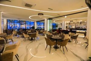 un restaurante con mesas y sillas y un bar en Maksimilian Apartament, en Durrës