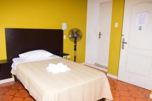 a bedroom with a bed with a white blanket and a fan at Hotel Casa Real Tacna in Tacna
