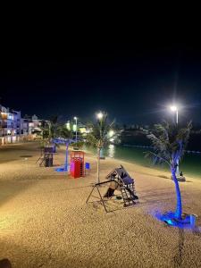 a beach with playground equipment and palm trees at night at درة العروس - فن بيتش in Durat Alarous