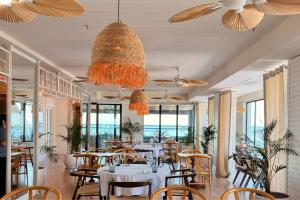a restaurant with white tables and chairs and windows at The Grandeur Hotel in Batumi