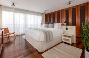 Schlafzimmer mit einem großen weißen Bett und Holzwänden in der Unterkunft Casa Mallet by Wynwood House in Panama-Stadt