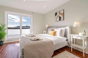a white bedroom with a large bed and a window at Bright Beachside Flat with Terrace by HostWise in Matosinhos