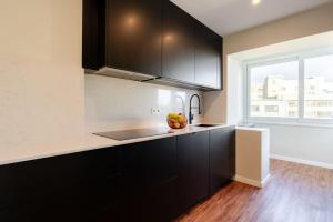 a kitchen with black cabinets and a window at Bright Beachside Flat with Terrace by HostWise in Matosinhos