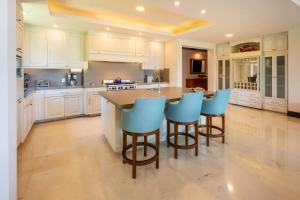 una cucina con armadi bianchi e sgabelli blu. di Ocean View Stay Golf Cart & Spa Access a Punta Mita