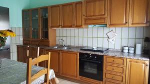 a kitchen with wooden cabinets and a sink and a stove at Tra L'Etna e il Mare in Giarre