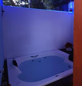 a white bath tub in a bathroom with a window at Chalé com jacuzzi Florianópolis in Florianópolis