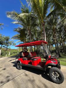 un golf cart rosso parcheggiato su una strada con palme di Elegant Golf View in Hacienda de Mita Beach Clubs a Punta Mita