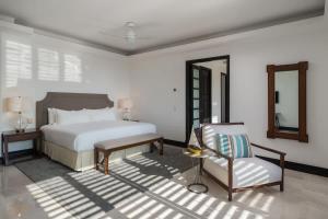 una camera da letto bianca con un letto e una sedia di Elegant Golf View in Hacienda de Mita Beach Clubs a Punta Mita