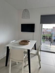 Una mesa y sillas blancas en una habitación con ventana. en Entre vientos, en La Porteña