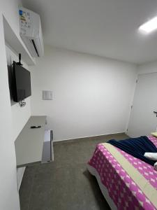 ジョアンペソアにあるManaira Suite 02のベッドと壁にテレビが掛かった寝室