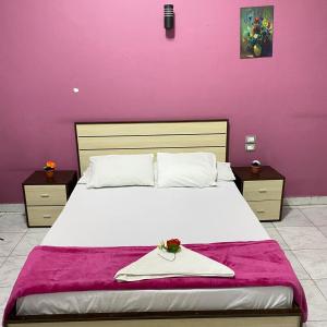 Un dormitorio con una cama grande con una pared morada. en Hostgram Home - Talaat Harb Square, en El Cairo