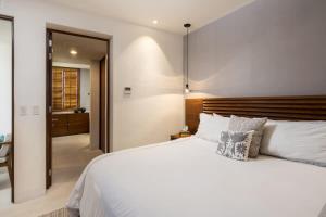 een slaapkamer met een wit bed met een houten hoofdbord bij Tropical Oceanview Condo Punta Mita in Punta Mita