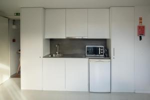a white kitchen with a sink and a microwave at I Loft Porto in Porto