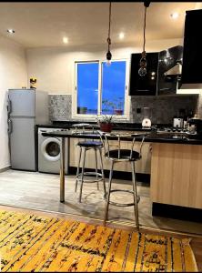 卡萨布兰卡Moderne appartement in a good location的厨房配有桌子和2把酒吧凳