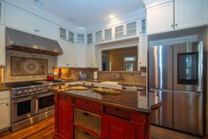 una gran cocina con armarios blancos y una isla roja en Misty Lane, en Edisto
