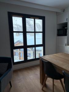 een eetkamer met een tafel en een groot raam bij Cosy Arc 1950, Ski-in Ski-out with Interior Swimming Pool, Sauna & Hammam in Arc 1950