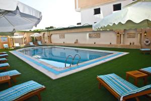 a large swimming pool with chairs and an umbrella at Hôtel César Palace in Sousse