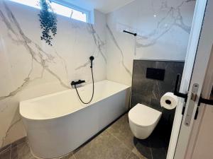 a bathroom with a bath tub and a toilet at Stylish private-entrance studio with bath and shower near Nijmegen Centre and Arnhem Zuid in Nijmegen +14 photos
