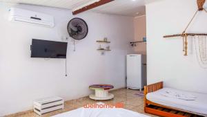 Zimmer mit einem Kühlschrank und einem TV an der Wand in der Unterkunft Pouso da Pardoca in Santa Cruz