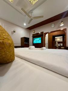 1 cama blanca grande en una habitación con TV en Serene stays, en Karachi