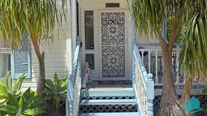 una porta d'ingresso bianca con un cancello e delle palme di Bromyard Cottage a Swansea