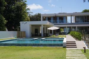 uma casa com uma piscina na frente em Casa Boutique Pontal da Ilha - 5 suítes - 14 pessoas em Itamaracá