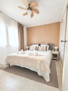 a bedroom with a large white bed with a ceiling fan at Casa Estío - Renovated 1st line sea view apartment, pool access, AC - Calpe Costa Blanca in Ifach