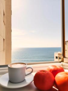 a cup of coffee on a table with two tomatoes at Casa Estío - Renovated 1st line sea view apartment, pool access, AC - Calpe Costa Blanca in Ifach