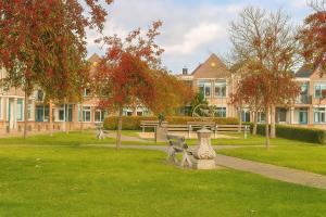 einen Park mit Bänken, Bäumen und Gebäuden in der Unterkunft De Strandgaper Egmond in Egmond aan den Hoef + 15 Fotos