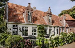 ein großes weißes Haus mit rotem Dach in der Unterkunft De Strandgaper Egmond in Egmond aan den Hoef