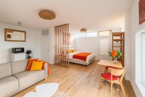 ein Wohnzimmer mit Sofa und Bett in der Unterkunft De Strandgaper Egmond in Egmond aan den Hoef