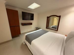 ボゴタにあるLavid Hotel Palacio Realの白いベッドと鏡のある寝室
