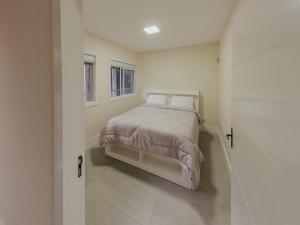 a bedroom with a bed and two windows at Recanto das Pedras Lodgin in Santa Maria do Erval
