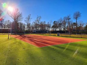a tennis court with the sun shining on it at Tiny House cosy pour une parenthèse nature in Marcilly-sur-Eure