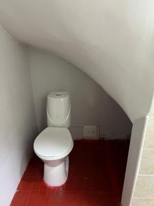 Un inodoro blanco en un baño con suelo de baldosas rojas. en The Mountain Apto House, en Bogotá