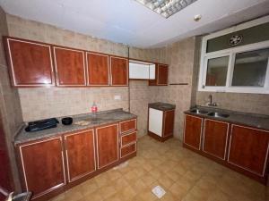 an empty kitchen with wooden cabinets and a sink at Fully Furnished Private Room in Abu Dhabi Intl