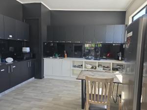 eine Küche mit weißen Schränken, einem Tisch und einem Kühlschrank in der Unterkunft SpinCity Lodge Auckland in Auckland