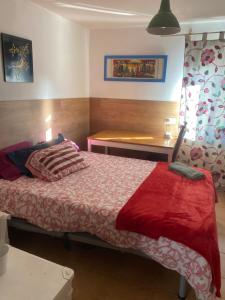 a bedroom with a bed with a red blanket and a table at El Doblao del Rey in Torrejón del Rey