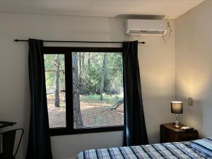 una camera da letto con una finestra con vista sulla foresta di ecuestre53 a Pinamar