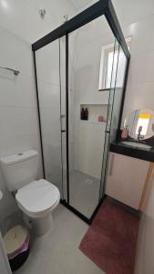a bathroom with a toilet and a glass shower at Apartamento no Centro de Mongaguá, perto da praia! in Mongaguá +22 photos