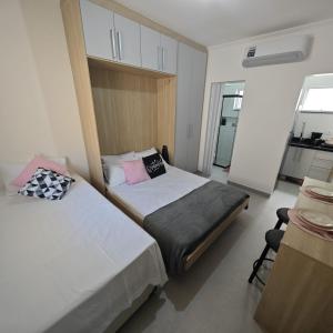 two beds in a small room with a kitchen at Apartamento no Centro de Mongaguá, perto da praia! in Mongaguá