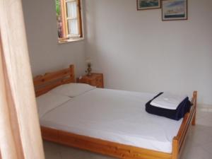 um quarto com uma cama de madeira e lençóis brancos em The Schoolmistress With The Golden Eyes, studios & rooms em Metímna