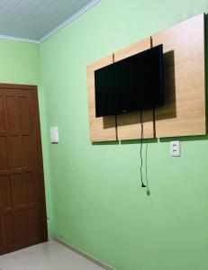 a flat screen tv hanging on a wall at kitnet 1 quarto in Arroio do Silva +8 photos