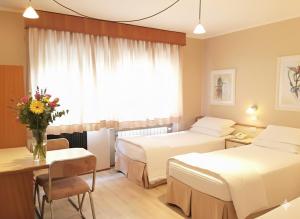 a hotel room with two beds and a table at Cosmos Hotel in Caxias do Sul