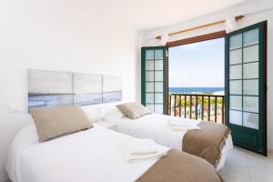 two beds in a bedroom with a view of the ocean at Atlantic & Teide Views Penthouse in Puerto de la Cruz