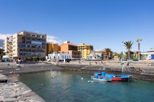 a blue boat in the water near a beach at Atlantic & Teide Views Penthouse in Puerto de la Cruz